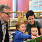 Minister Doug Currie reads a story with Charlie and Rosie and their mother Jinny Greaves.