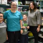 Photo shows two grade three students standing with two adults in a kitchen environment