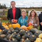 Photo shows a group of six people standing with a cart of pumpkins and gourds.