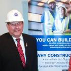 Three people standing beside each other wearing hard hats and a banner sign is behind them