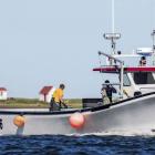 Fishing boat sails past Souris lighthouse