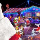Santa's hand holding a smartphone showing his Vax Pass, with a seasonally decorated house in the background