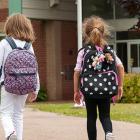 three children walking toward a school