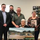 Minister Myers and four Islanders stand behind a woman sitting holding a large photo of the proposed Tignish co-op expansion