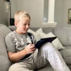Young boy using an iPad on a sofa