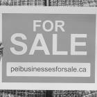 Image of woman holding a FOR SALE sign that lists the peibusinessesforsale.ca website address 