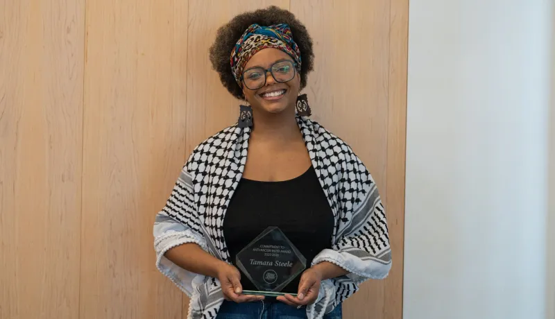 A smiling Black woman holds her award.