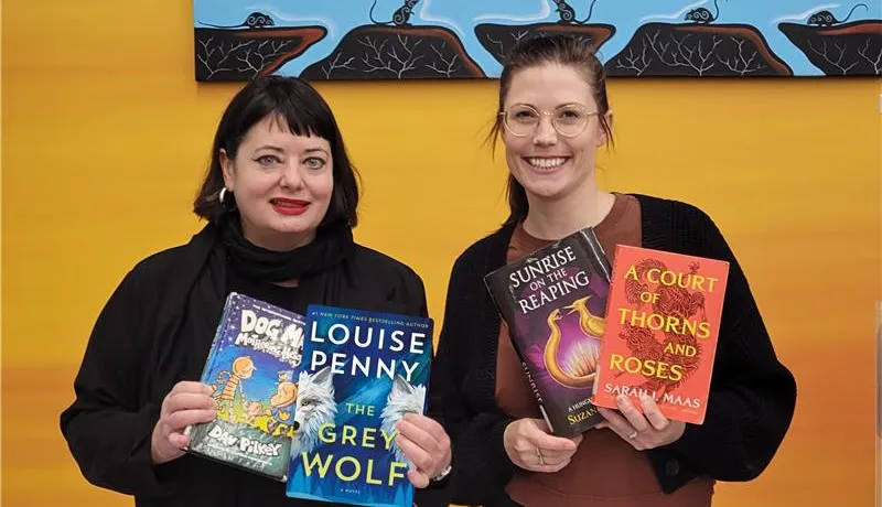 Two women librarians hold several books from the top pics list.