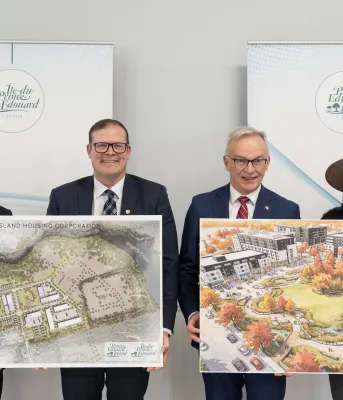 Four people stand together holding diagrams of the future development.
