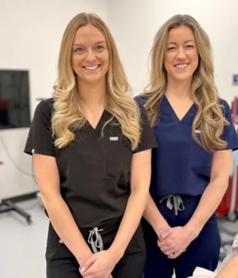 Deux femmes blondes aux cheveux longs sourient l'une à côté de l'autre.