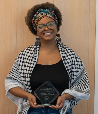 A smiling Black woman holds her award.