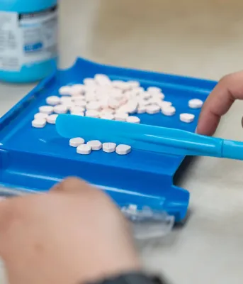 White pills placed on a blue platform to be counted.