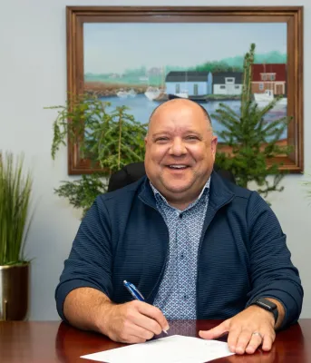 The Minister sits at his desk with different types of sapling trees around him.