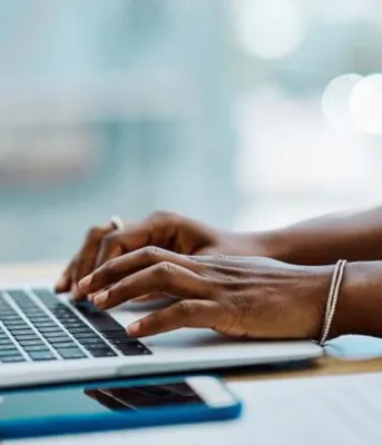 Une femme noire tape sur un ordinateur.