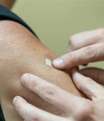 A doctor applies a bandaid to a person&#039;s arm after vaccination.