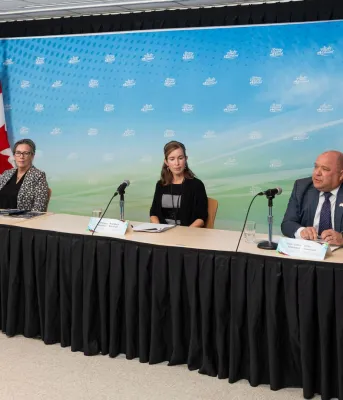 Two men and two women sit at a long table with a colorful backdrop.