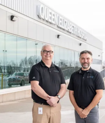 Deux hommes se tiennent à l'extérieur de l'hôpital Queen Elizabeth.