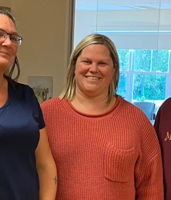 Three smiling women standing next to each other.