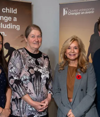 Three women and one man stand in front of the foster campaign posters.