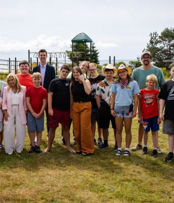 Les enfants et les adultes se rassemblent devant le terrain de jeux au Camp Gencheff.