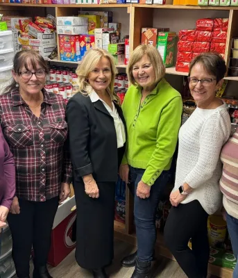 The minister and five women stand together in a food pantry.