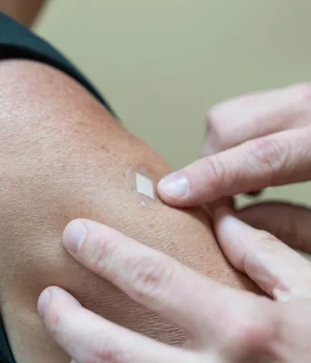 Un bras avec un petit band-aid couvrant le site de vaccination récent.