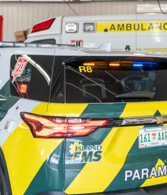 Une camionnette EMS marquée en jaune et vert garée devant une ambulance.