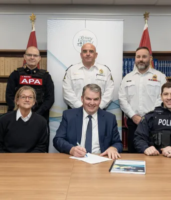 The minister and five officers stand in front of a bookcase.