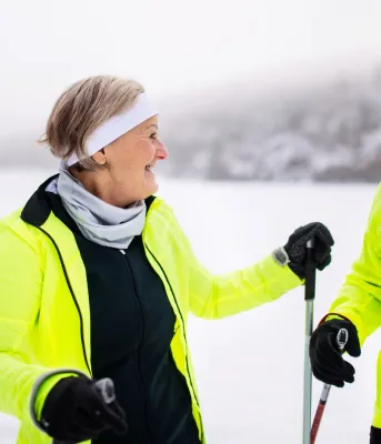 And elderly couple hiking in winter with ski poles.