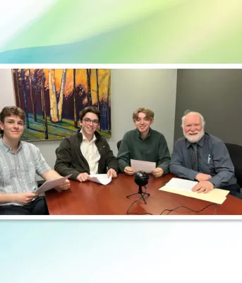 image of four people siting at a table with a recording microphone on the table