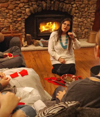 A cozy scene of people sitting around a woodstove.
