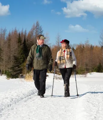 Un couple âgé fait de la randonnée en hiver avec des bâtons de ski.