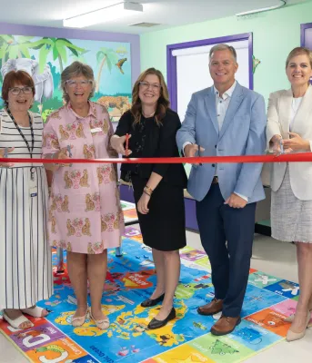 Sept personnes se sont rassemblées dans une zone Smilezone colorée pour couper le ruban cérémoniel.