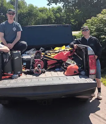 Four youth stand around a truck outside.