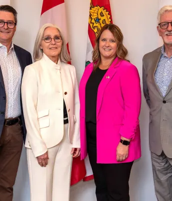 Les quatre personnes citées se tiennent côte à côte après l'annonce.