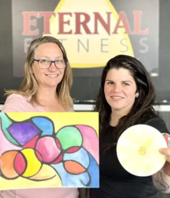 Une femme blonde et une femme brune se tiennent devant le panneau de l'Eternal Wellness.