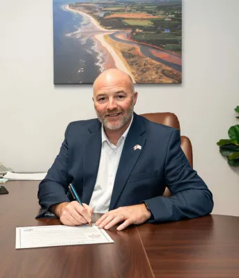 The Minister signing a proclamation at his desk.