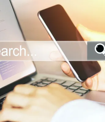 Image of individual using a laptop with text that reads "search"