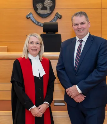 The new judge and the minister stand next to each other in the courthouse.