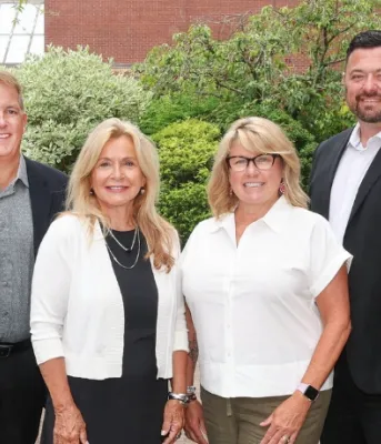 Quatre personnes debout et souriantes