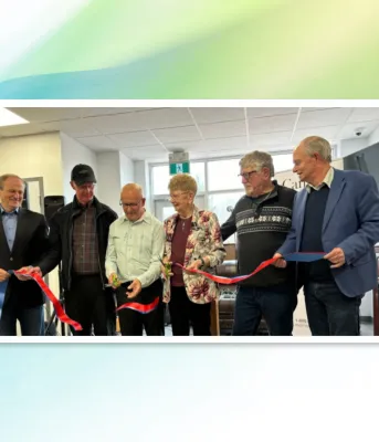 image of six people in a room standing shoulder to shoulder and one person is cutting a ribbon held by all of them