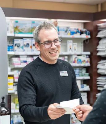 Un pharmacien remet une ordonnance à une femme.