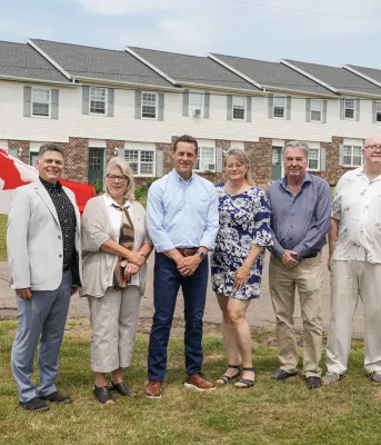 Six personnes debout devant des logements