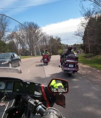 Image taken from viewpoint of motorcycle driver on rural PEI road with other motorcycles in front and car in opposing lane