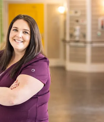 PEI resident care worker in scrubs standing in hallway
