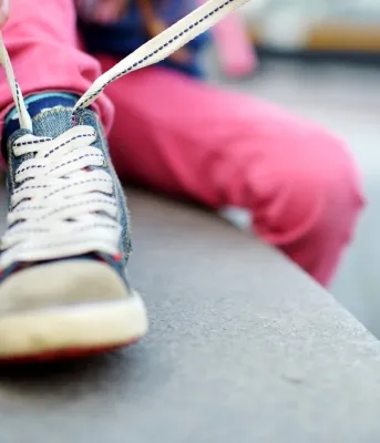 Image of small child tying shoe laces