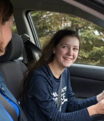 Young driver sits in driver seat with adult on passenger side