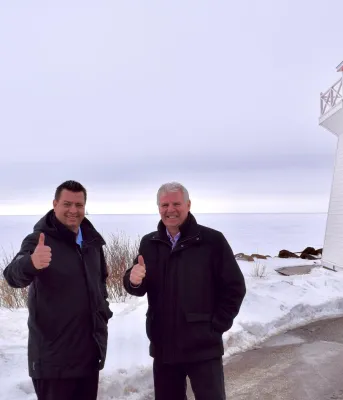 Two people standing shoulder to shoulder on a wharf