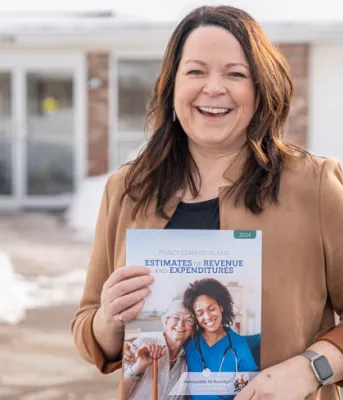 image of a person outside of a building holding a document in front of her