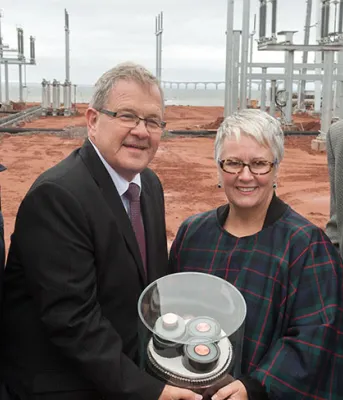 Four people holding underwater cable sample at Borden electric substation.